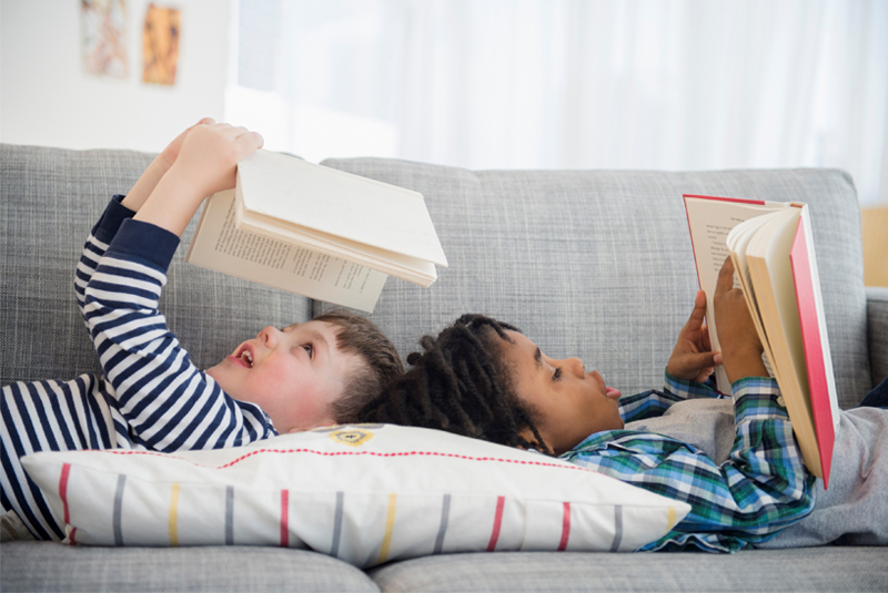 2 enfants lisant un livre sur le canapé