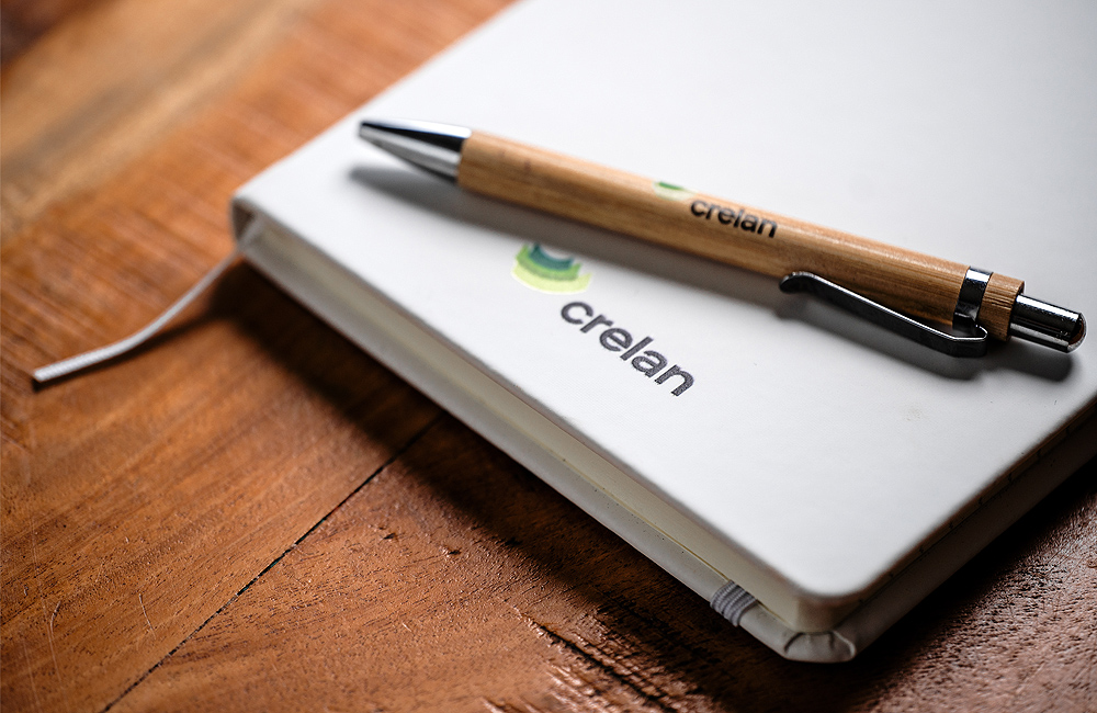 Un agenda et un stylo avec le logo Crelan sont posés sur un bureau