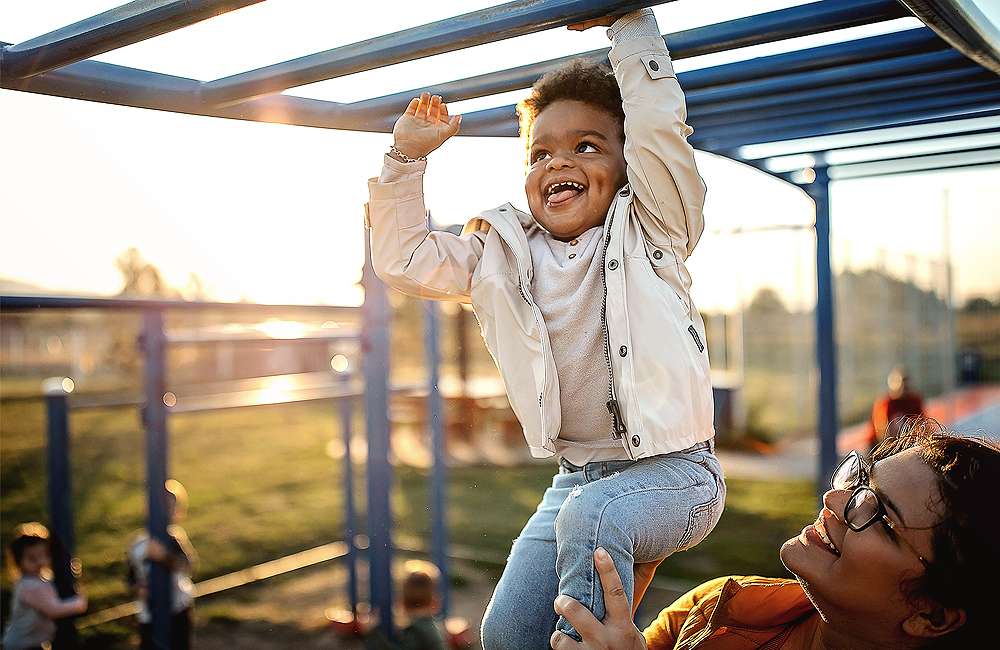 Un petit garçon joue joyeusement sur un portique d'escalade avec sa mère
